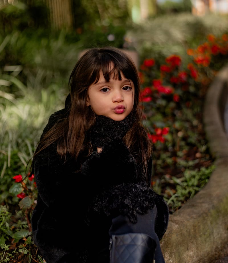 Retrato da filha, de franjinha, num jardim florido